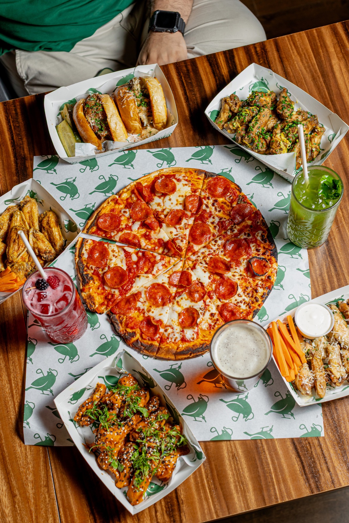 Mesa con pizza, alitas, sliders y bebidas de Birdies & Beers